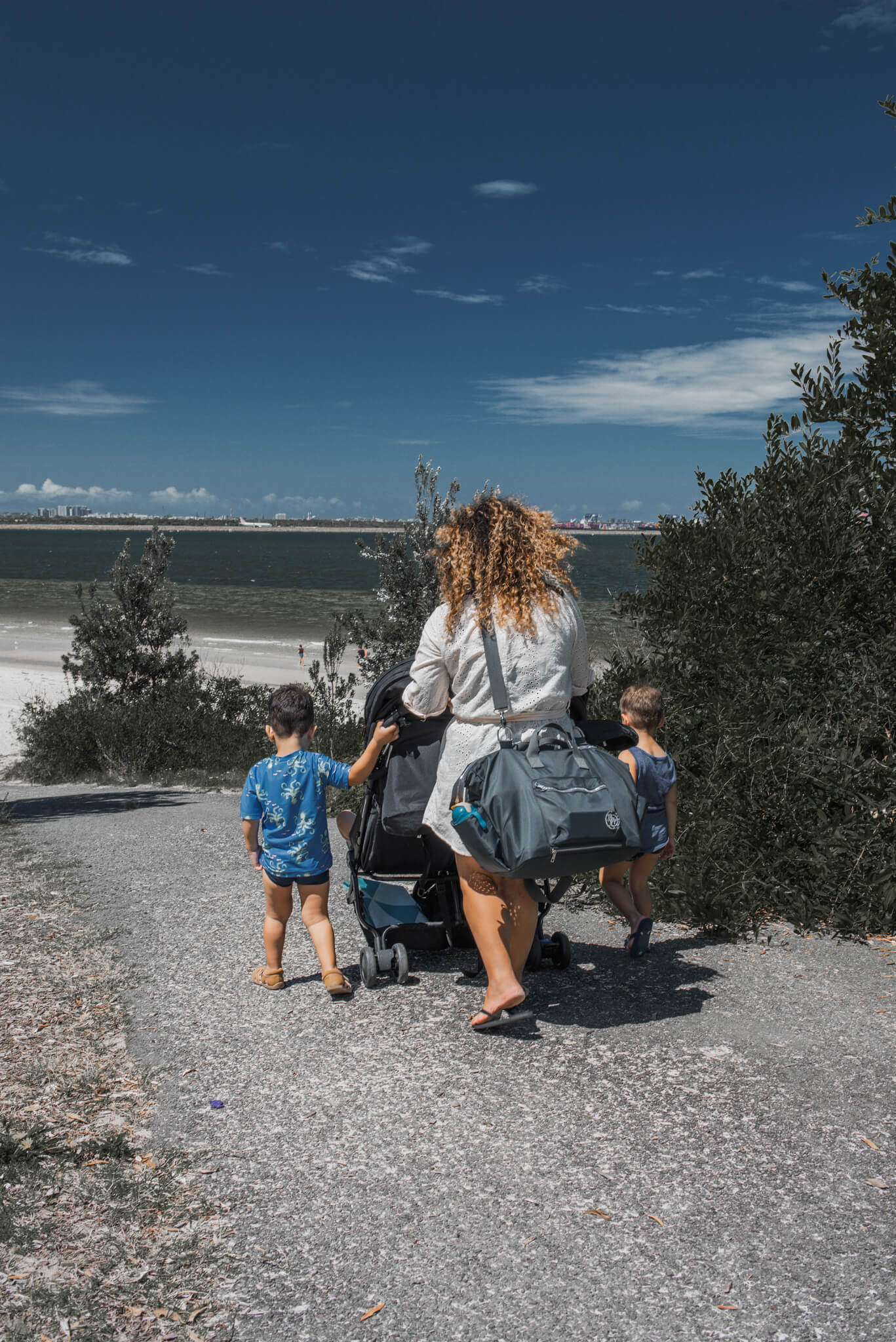 twin mum walking to beach with duffle baby bag 