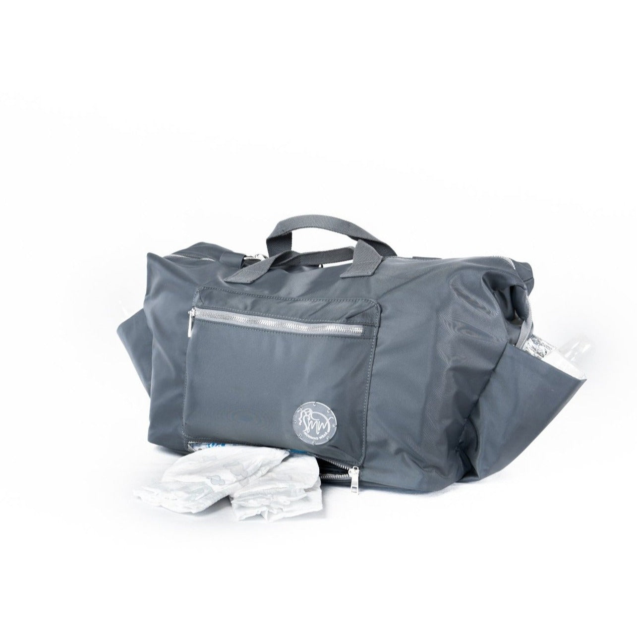 alt="The DUFFLE Nappy Bag showing secret bottom zipper compartment opened and nappies"