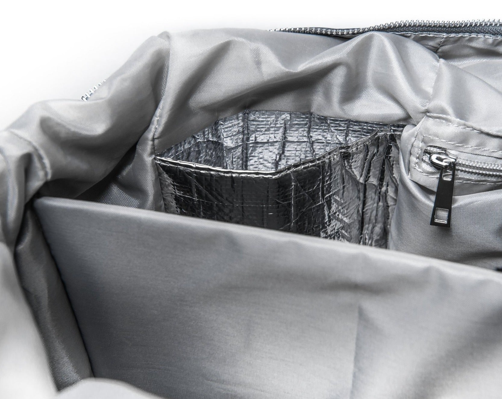 alt="inside The DUFFLE Nappy Bag insulated drink pocket, internal zipper pocket and the wall of the insulated snack compartment"